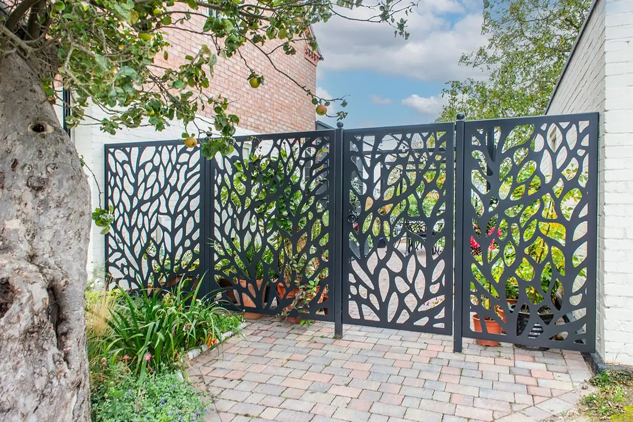 Decorative metal garden gate with foliage pattern in a garden setting.